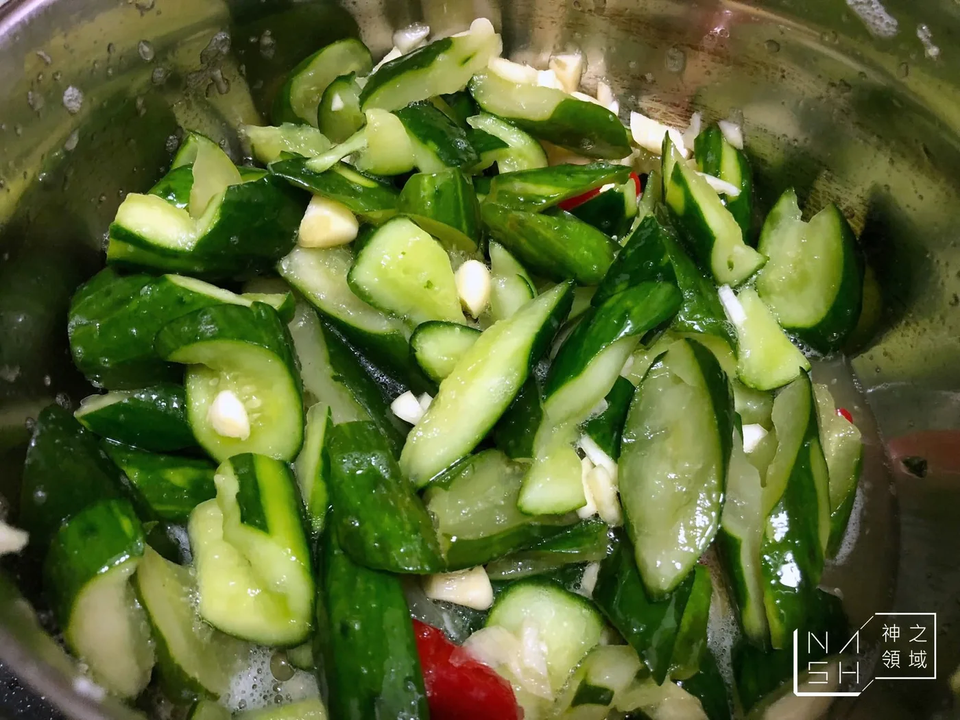透明容器中的涼拌小黃瓜，附蒜片與辣椒